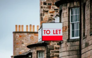 A-TO-LET-sign-hanging-on-the-side-of-a-building-with-a-cloudy-sky-Total-Guaranteed-Rent