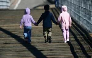 Three-children-walking-hand-in-hand-representing-the-importance-of-safe-spaces-like-Childrens-Homes-in-the-UK.