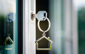 Close-up-of-a-key-in-a-door-with-a-house-shaped-keychain-related-to-renting-properties