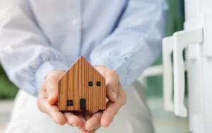 Hand-holding-wooden-house-symbolizing-Rental-Assurance