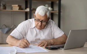 Landlord-signing-documents-with-laptop-and-calculator-guaranteed-rent