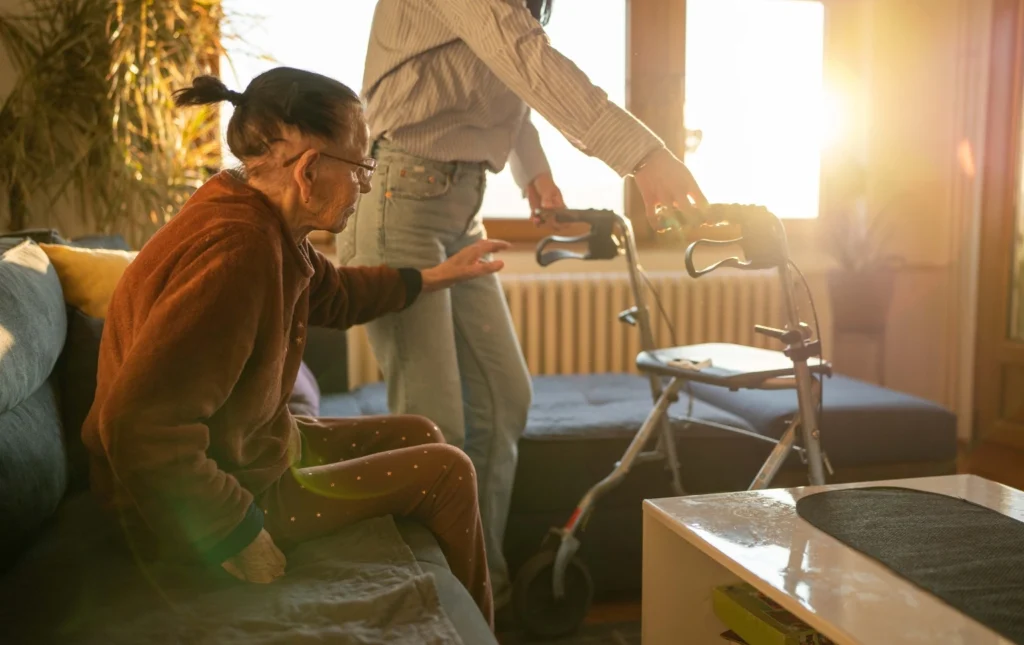 Caregiver-assisting-elderly-person-with-walker-in-supported-living-room-with-natural-light