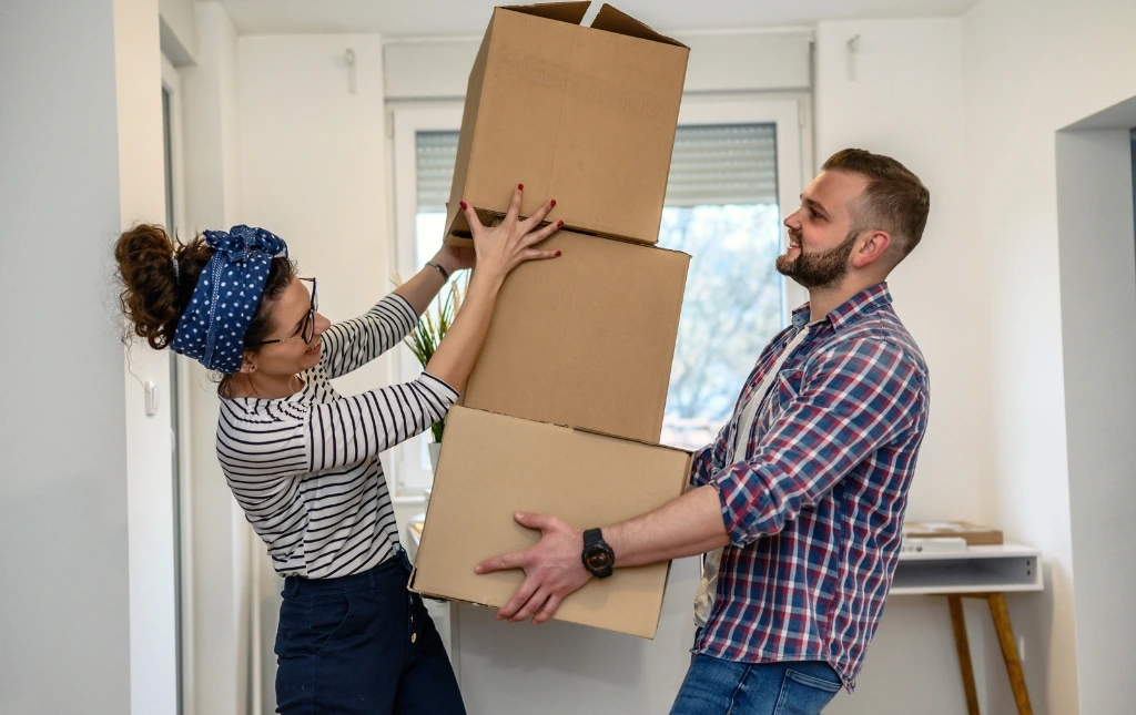 Couple-balancing-moving-boxes-with-smiles-navigating-changing-regulations-with-our-guaranteed-rent-solutions