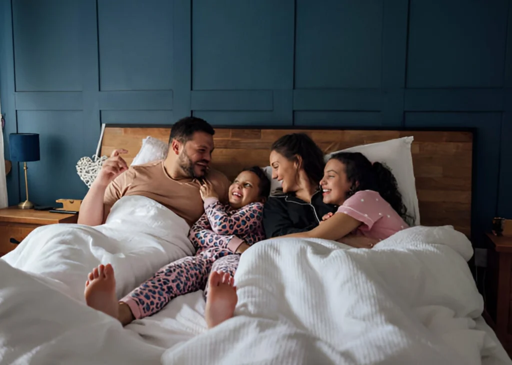 Family-enjoying-quality-time-in-bed-together-at-hotel-room