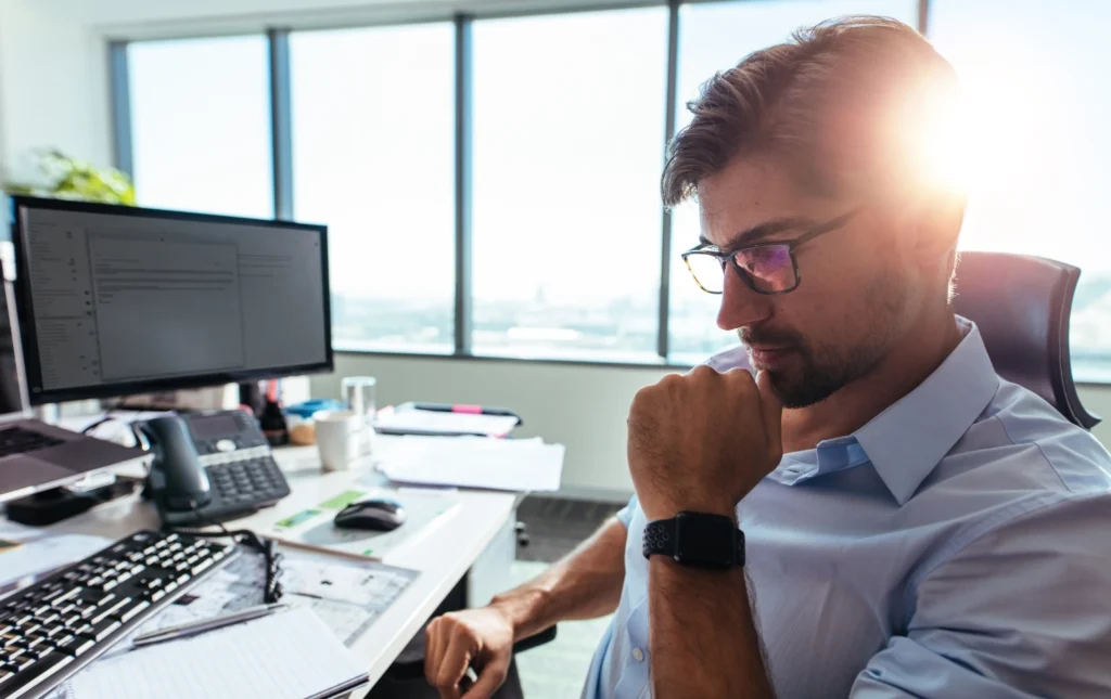 Fund-manager-working-at-desk-with-computer-and-strategic-plans