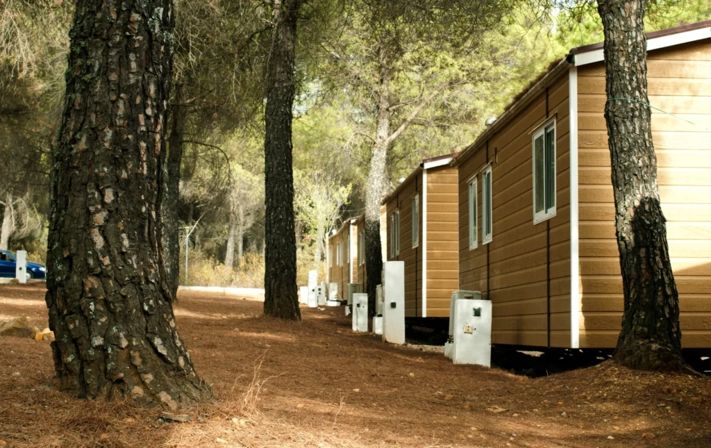 Row-of-temporary-accommodation-cabins-surrounded-by-trees-in-a-forested-area