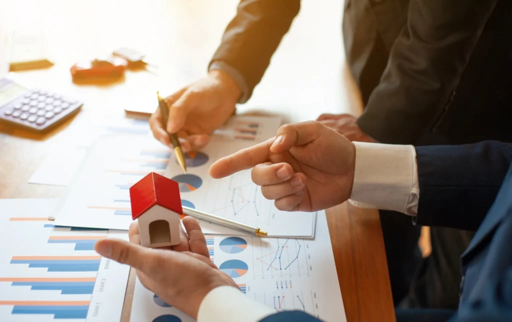 Two-business-people-reviewing-charts-with-a-small-house-model-symbolizing-landlord-updates-prem-property