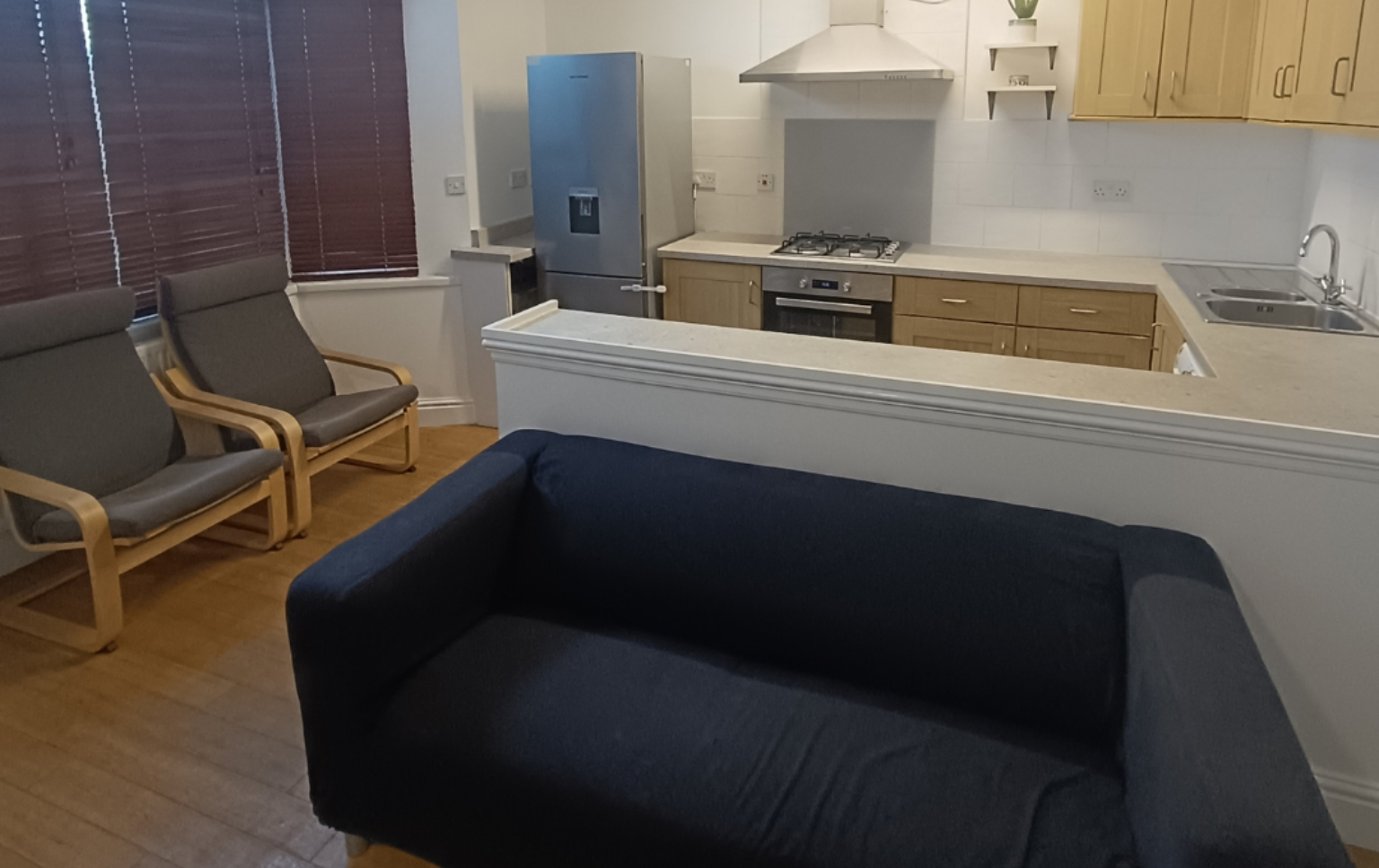 A-living-room-with-a-couch-two-chairs-and-a-kitchen-area